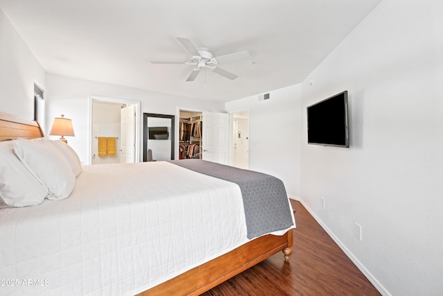 bedroom with visible vents, wood finished floors, baseboards, connected bathroom, and a spacious closet