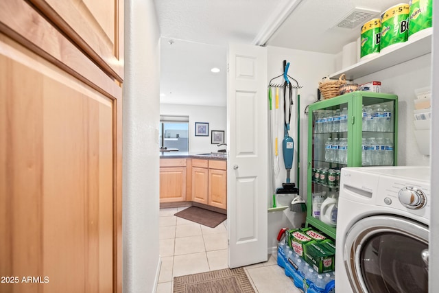 washroom with visible vents, laundry area, light tile patterned flooring, washer / clothes dryer, and a sink