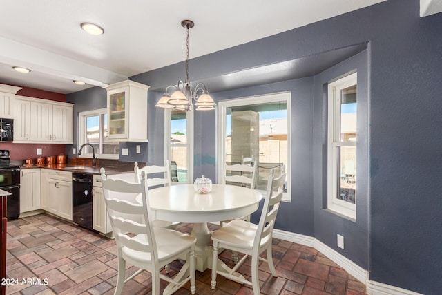 kitchen with an inviting chandelier, glass insert cabinets, baseboards, white cabinets, and black appliances