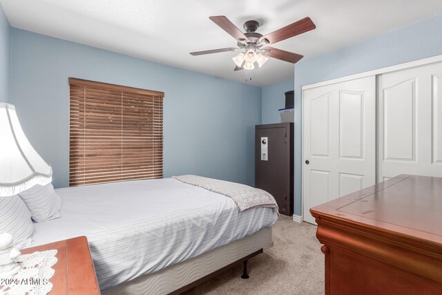 bedroom with ceiling fan, light carpet, and a closet