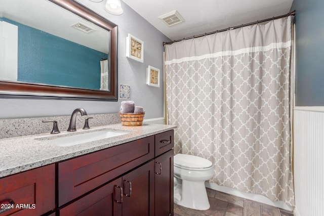 full bath featuring toilet, visible vents, stone finish floor, and vanity
