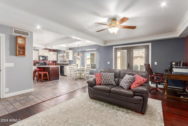living room with crown molding, baseboards, visible vents, and ceiling fan with notable chandelier