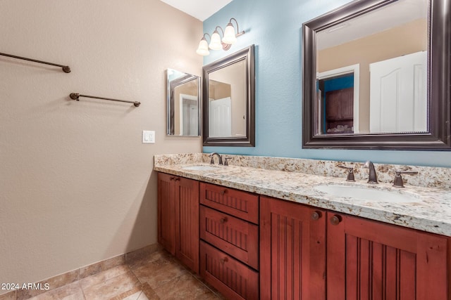 bathroom with a sink, baseboards, and double vanity