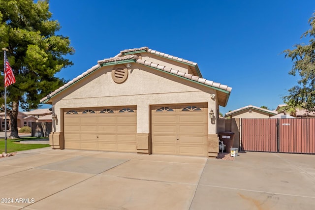 view of front facade with a tile roof, driveway, a gate, and stucco siding