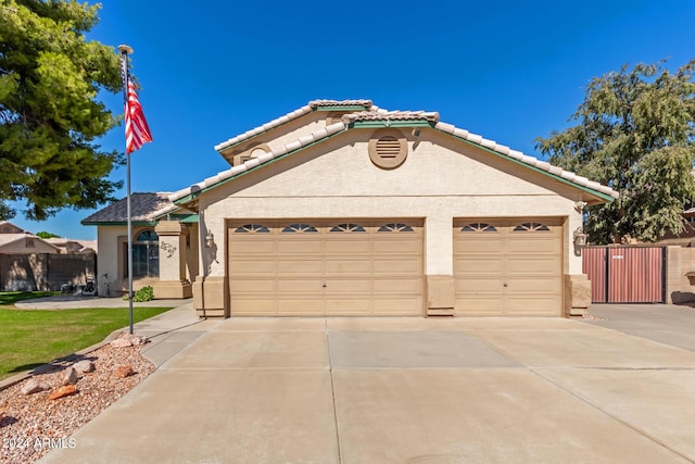 single story home with a garage, stucco siding, a gate, concrete driveway, and a tile roof