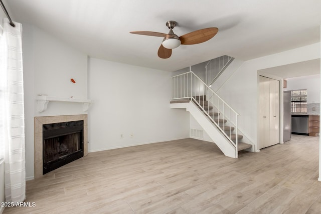 4901 E Kelton Ln Unit 1251, Scottsdale, AZ 85254 - unfurnished living room featuring a ceiling fan, a tile fireplace, stairway, and wood finished floors
