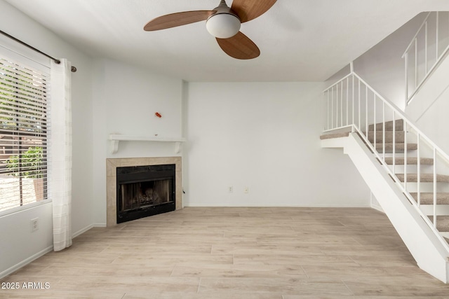 4901 E Kelton Ln Unit 1251, Scottsdale, AZ 85254 - unfurnished living room with ceiling fan, a tiled fireplace, wood finished floors, and stairway