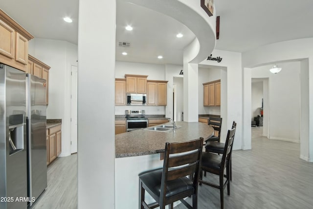 kitchen featuring sink, a breakfast bar area, light hardwood / wood-style flooring, appliances with stainless steel finishes, and a kitchen island