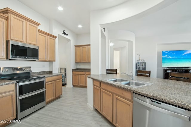 kitchen featuring appliances with stainless steel finishes, sink, and light wood-type flooring