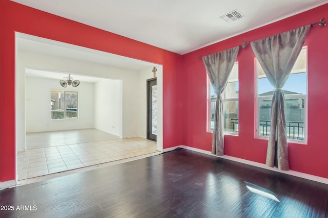 unfurnished room featuring a notable chandelier and hardwood / wood-style flooring