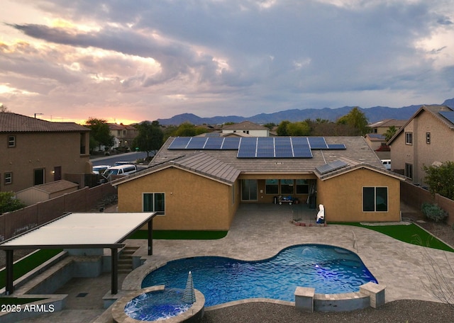 pool at dusk featuring a mountain view and a patio area