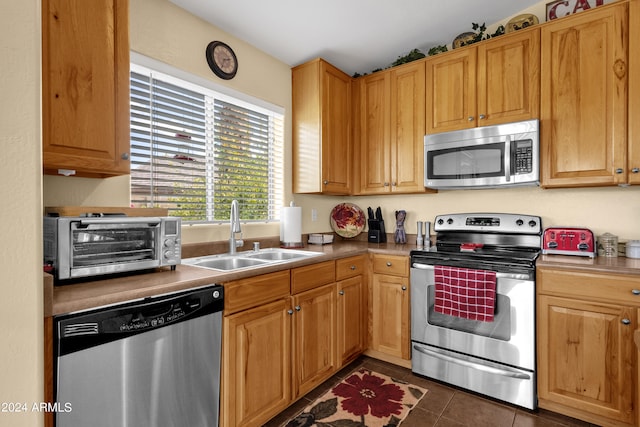 kitchen featuring appliances with stainless steel finishes, sink, and dark tile patterned floors