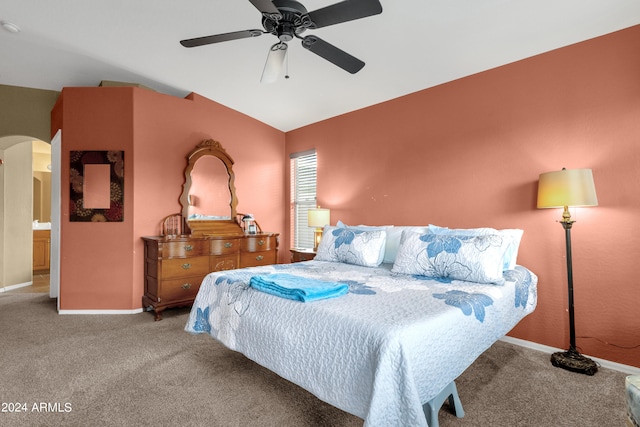 carpeted bedroom featuring lofted ceiling, ensuite bath, and ceiling fan