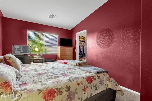 carpeted bedroom featuring vaulted ceiling, a walk in closet, and a closet