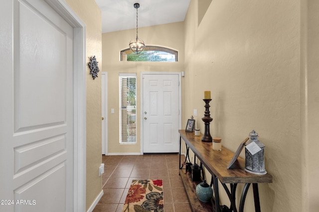 foyer featuring vaulted ceiling, a chandelier, and dark tile patterned flooring