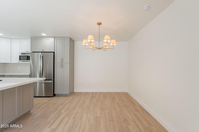 5132 N 83rd St, Scottsdale, AZ 85250 - kitchen featuring appliances with stainless steel finishes, a chandelier, light wood finished floors, light countertops, and backsplash