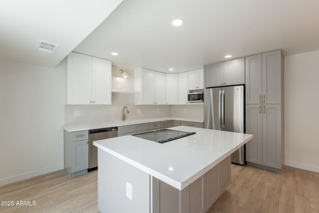 5132 N 83rd St, Scottsdale, AZ 85250 - kitchen with appliances with stainless steel finishes, a sink, baseboards, light wood finished floors, and a kitchen island