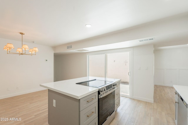 5132 N 83rd St, Scottsdale, AZ 85250 - kitchen with stainless steel range with electric cooktop, light wood-type flooring, a chandelier, a kitchen island, and light countertops