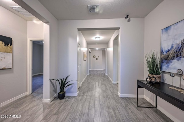 hall featuring a textured ceiling and light wood-type flooring