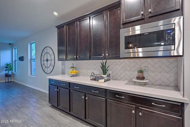 kitchen with backsplash, dark brown cabinetry, and light hardwood / wood-style flooring