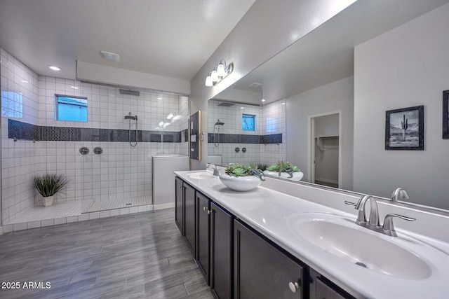 bathroom with tiled shower and vanity