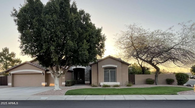 view of front of house with a front yard, fence, driveway, stucco siding, and a garage