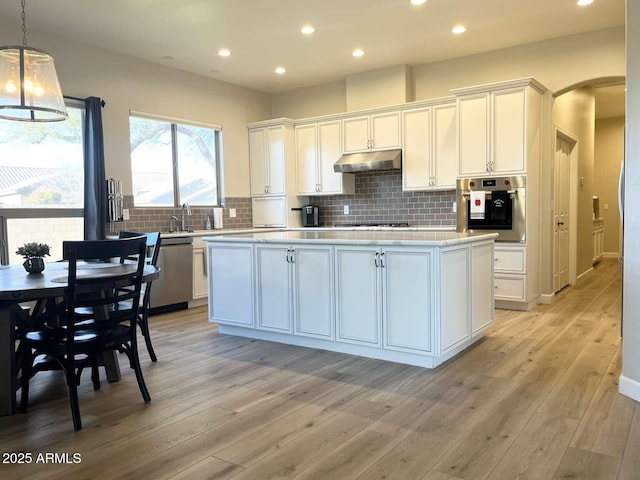 kitchen featuring under cabinet range hood, white cabinets, appliances with stainless steel finishes, and a center island