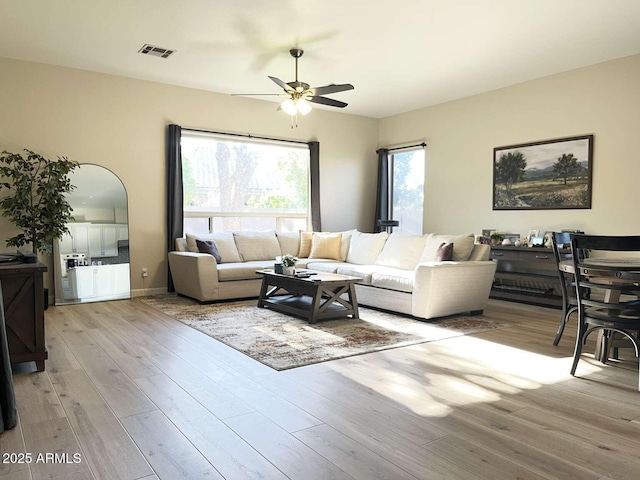 living room featuring visible vents, wood finished floors, baseboards, and ceiling fan