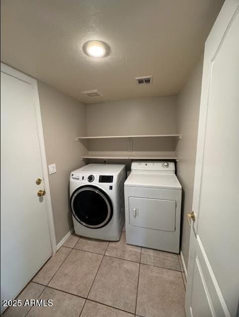 laundry room featuring washing machine and dryer, light tile patterned flooring, visible vents, and laundry area
