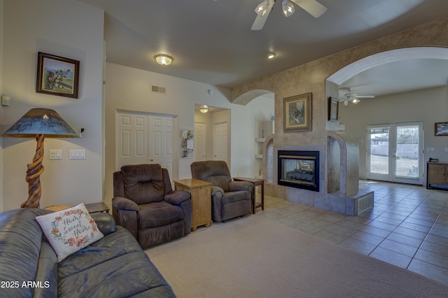 tiled living room featuring a tiled fireplace, built in features, and ceiling fan