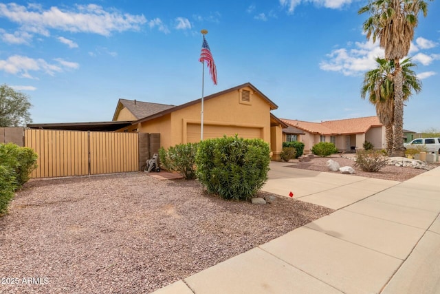 view of front of property with a garage, concrete driveway, a gate, fence, and stucco siding