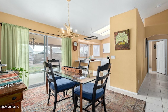 dining area with arched walkways, light tile patterned floors, lofted ceiling, a chandelier, and baseboards