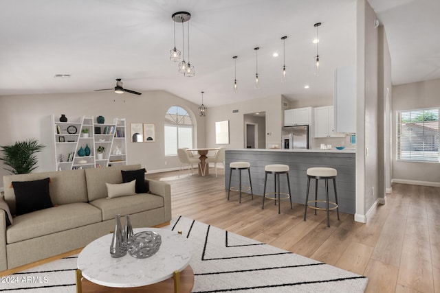 living room featuring ceiling fan, lofted ceiling, and light wood-type flooring