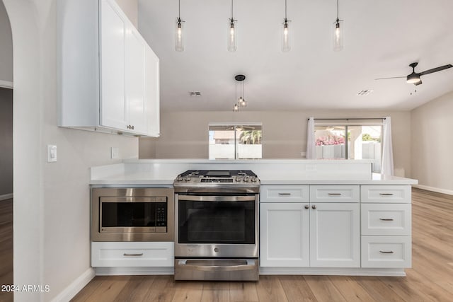 kitchen with pendant lighting, stainless steel appliances, white cabinetry, and a wealth of natural light