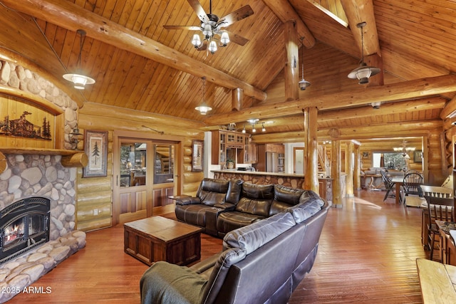 living room with high vaulted ceiling, a stone fireplace, light hardwood / wood-style floors, and beam ceiling