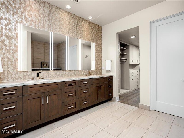 bathroom featuring double vanity, backsplash, and tile floors