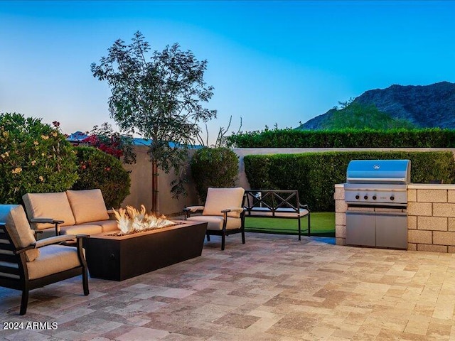 view of patio featuring a mountain view, an outdoor living space with a fire pit, and grilling area