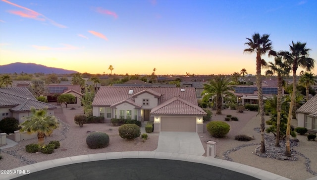 view of front of house with an attached garage, a mountain view, a tiled roof, driveway, and stucco siding