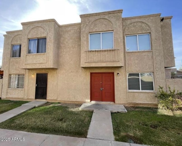 multi unit property with a front yard and stucco siding