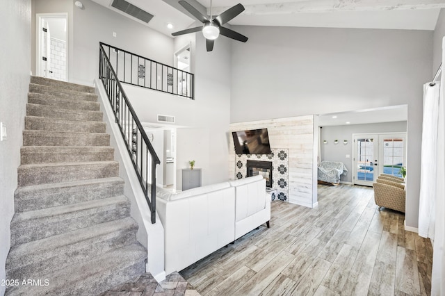 living room with a high ceiling, french doors, ceiling fan, and light wood-type flooring