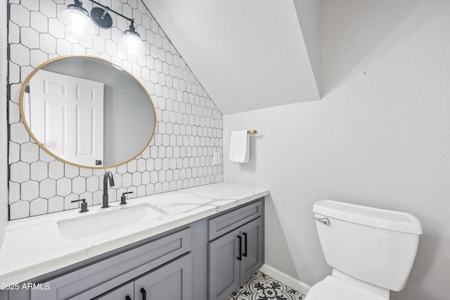 bathroom featuring vanity, lofted ceiling, backsplash, and toilet