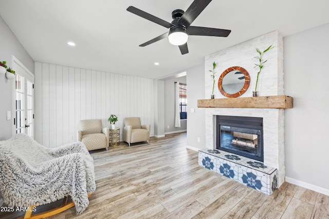 living room featuring ceiling fan, a fireplace, and light hardwood / wood-style flooring