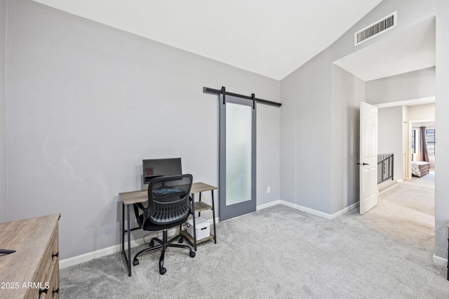 home office with light colored carpet, lofted ceiling, and a barn door