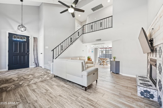 living room with a tiled fireplace, light hardwood / wood-style floors, and ceiling fan