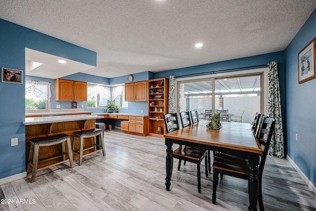 dining room with a textured ceiling and light hardwood / wood-style floors