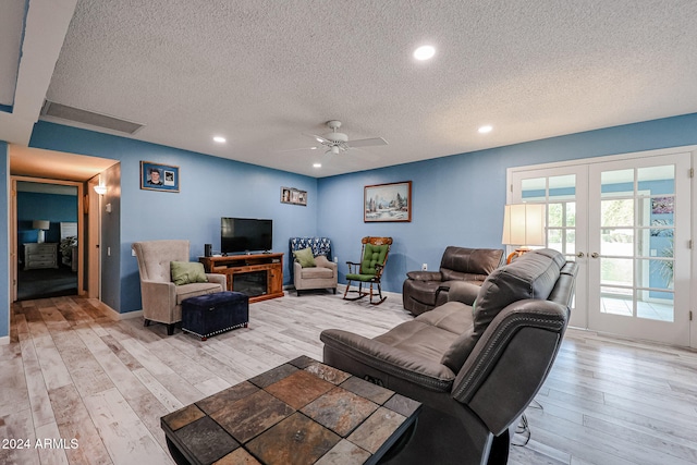 living room featuring french doors, light hardwood / wood-style floors, and a textured ceiling