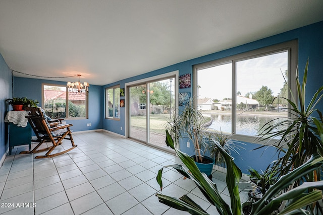 interior space with a water view, a healthy amount of sunlight, light tile patterned floors, and a notable chandelier