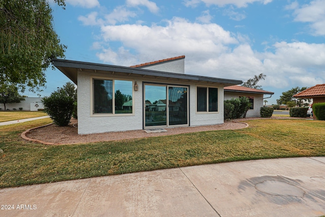 back of house featuring a lawn and a patio