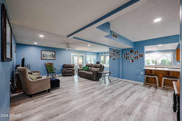 living room with ceiling fan, light hardwood / wood-style floors, a textured ceiling, and french doors