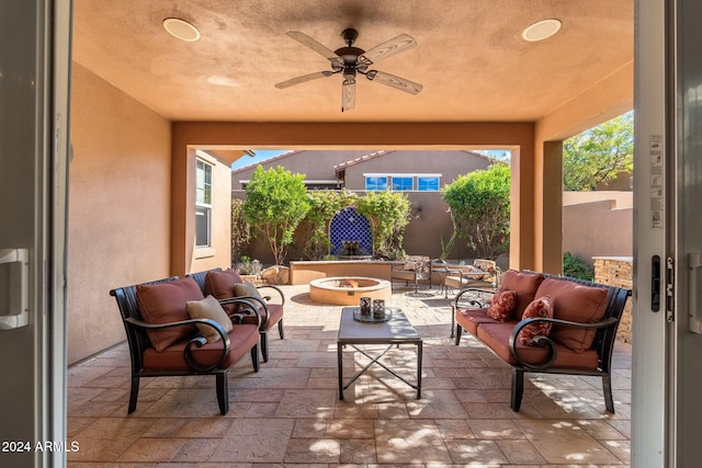 view of patio / terrace with ceiling fan and an outdoor living space with a fire pit